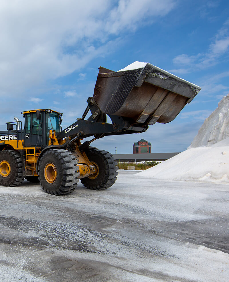 a john deere frontend loader scooping de-icing road salt