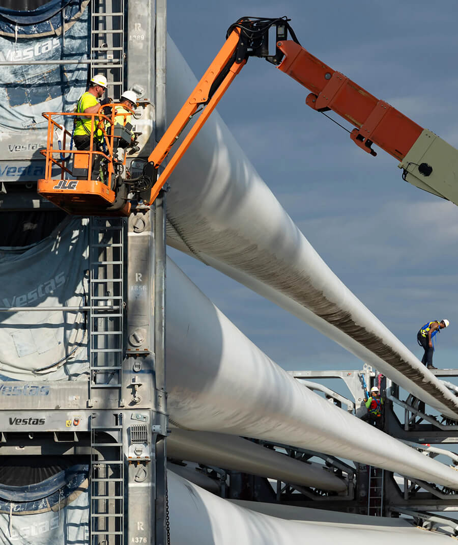 stevedores on a lift unloading wind turbine rotars